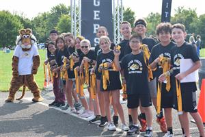 students stand at a race finish line with medals from a race