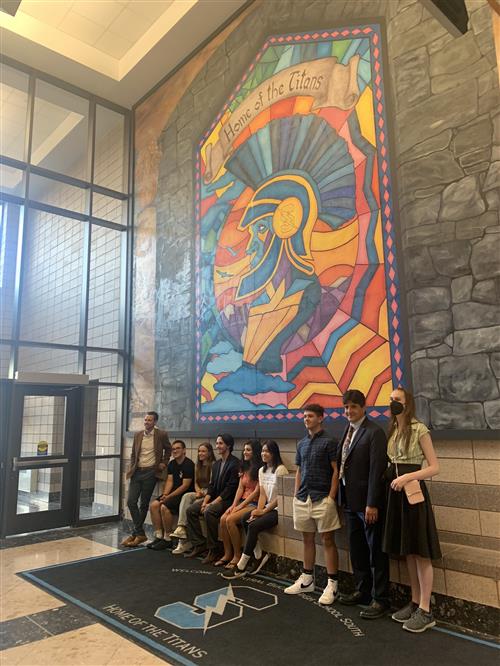 students and teachers stand before a colorful 20-foot mural of a cb south titan fashioned as a stained glass window 