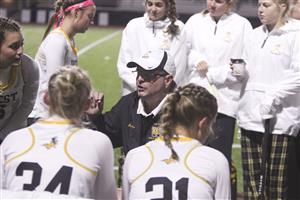 field hockey players gather around their coach