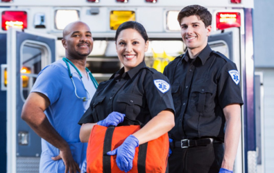  Three emergency workers pose for a photo in front of an ambulance.