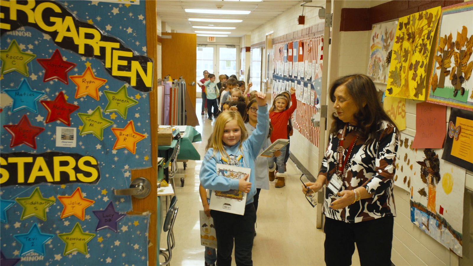 A teacher leads a kindergarten class out of the classroom
